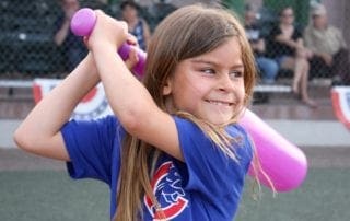 A young girl swinging a bat at a baseball game.