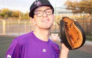 A young man with glasses holding a baseball glove.
