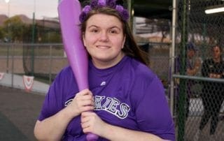A woman holding a purple baseball bat.