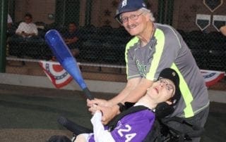 A man in a wheelchair holding a baseball bat.