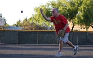 A man in a red shirt throwing a baseball.