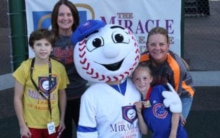 A group of people posing with a baseball mascot.