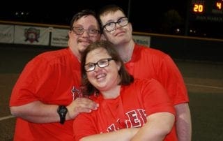 Three people posing for a picture on a baseball field.