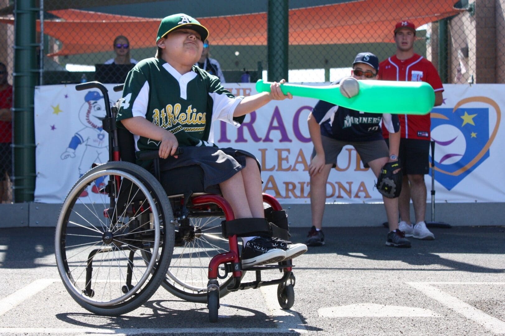 A man in a wheelchair holding a green bat.
