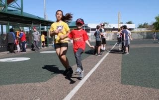 A woman and a child running on a baseball field.