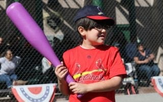 A young boy holding a purple baseball bat.