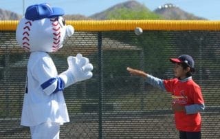 A boy is throwing a ball to a mascot.
