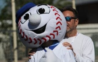 A man is hugging a baseball mascot.