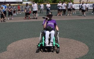 A boy in a wheelchair on a baseball field.