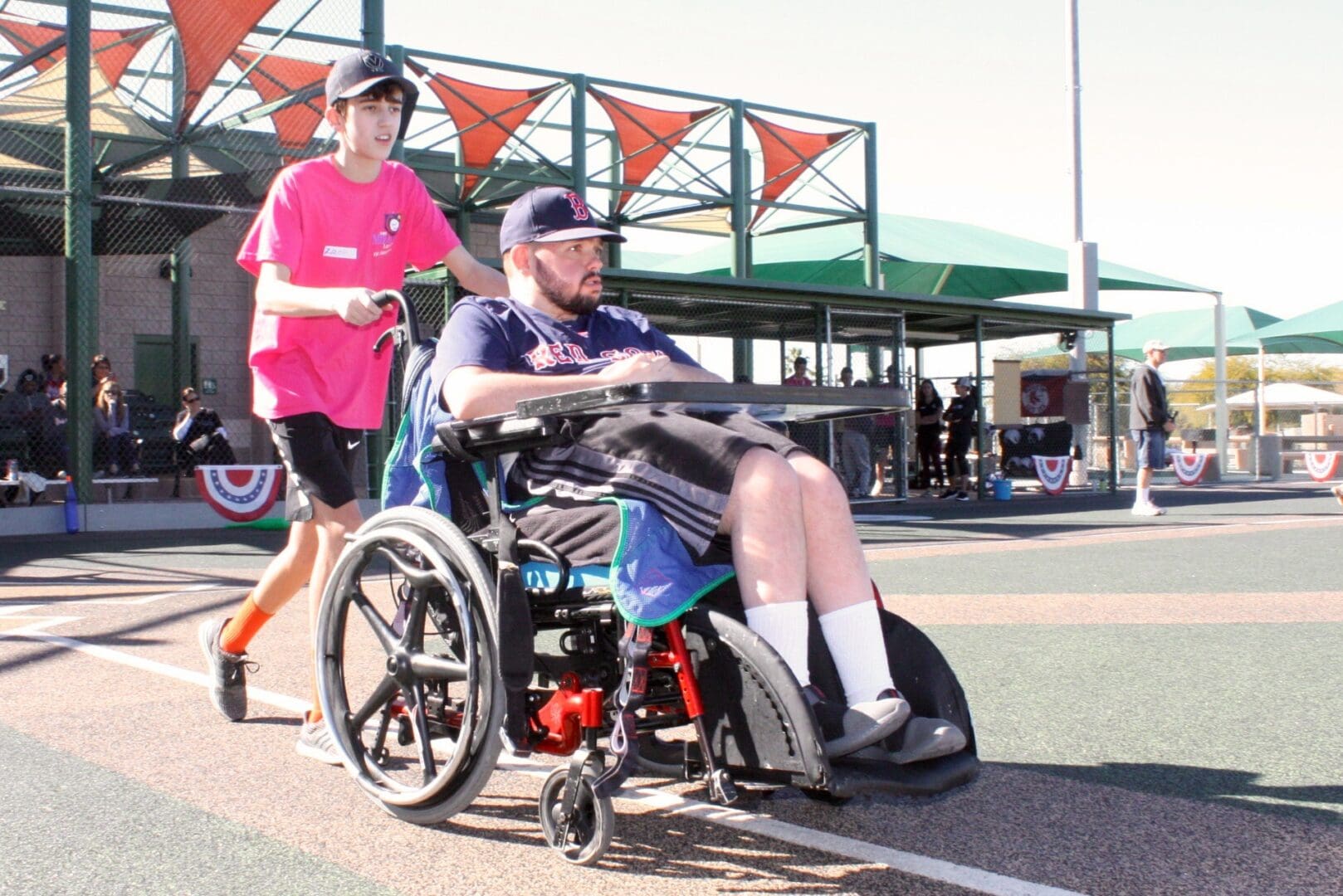 A man in a wheelchair is pushing another man on a tennis court.