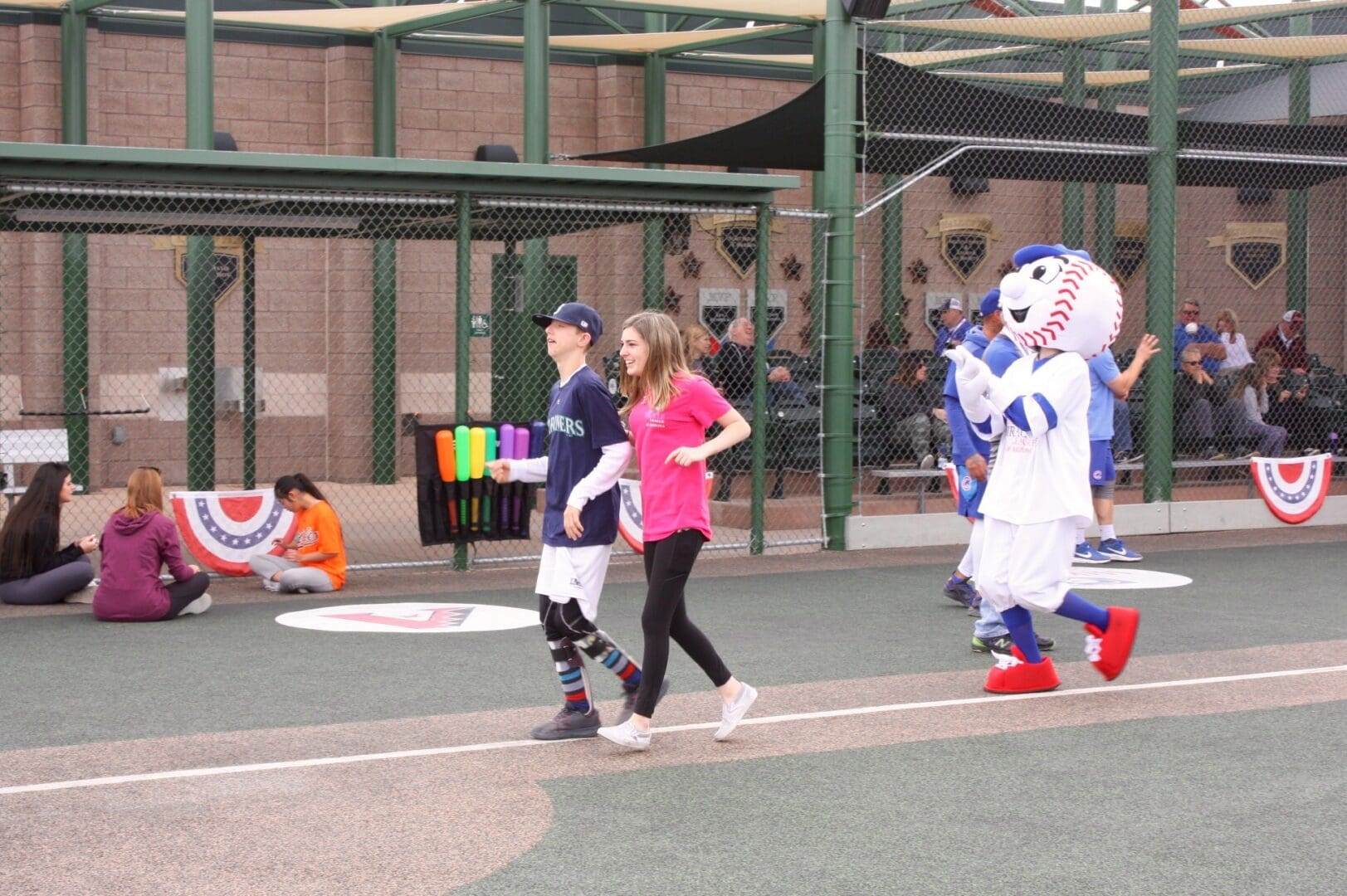 A group of people walking on a baseball field with a mascot.