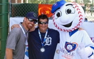 Three men posing for a photo with a baseball mascot.