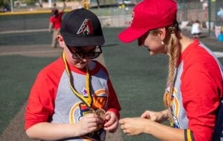 A woman is helping a young boy with a medal.