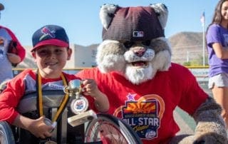 A boy in a wheelchair poses with a mascot.