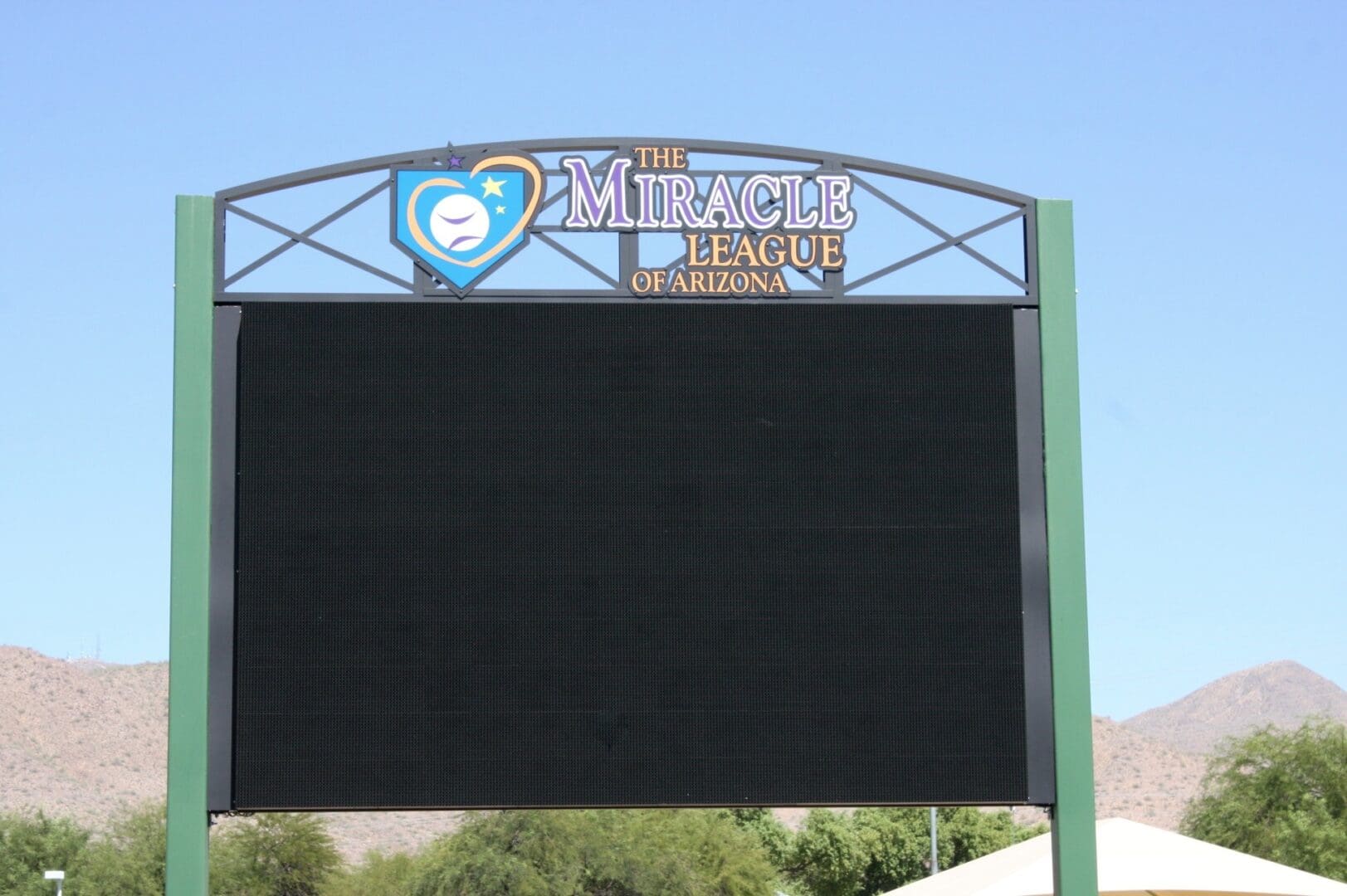 A baseball field with a scoreboard in front of it.