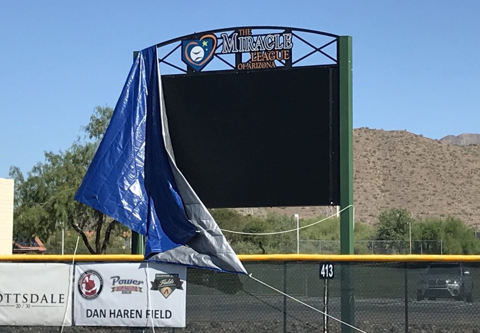 A baseball field with a blue flag in front of it.
