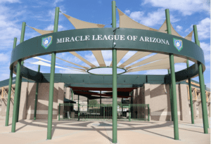 A large green sign is in front of the entrance to a baseball stadium.