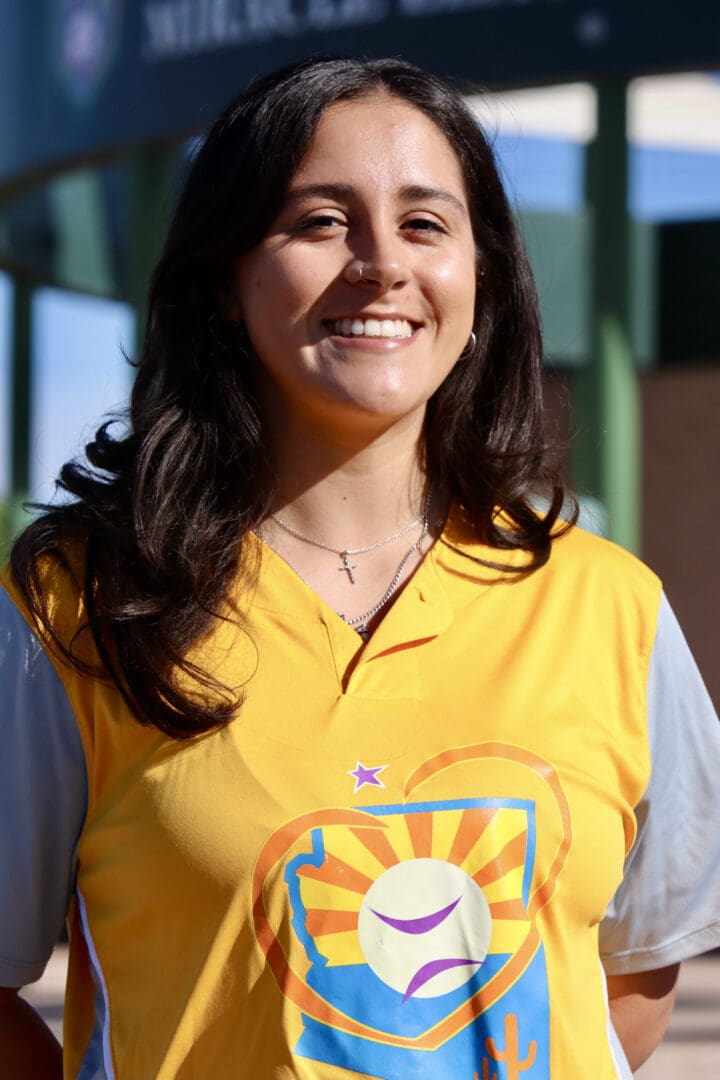 A woman in a yellow shirt smiling for the camera.