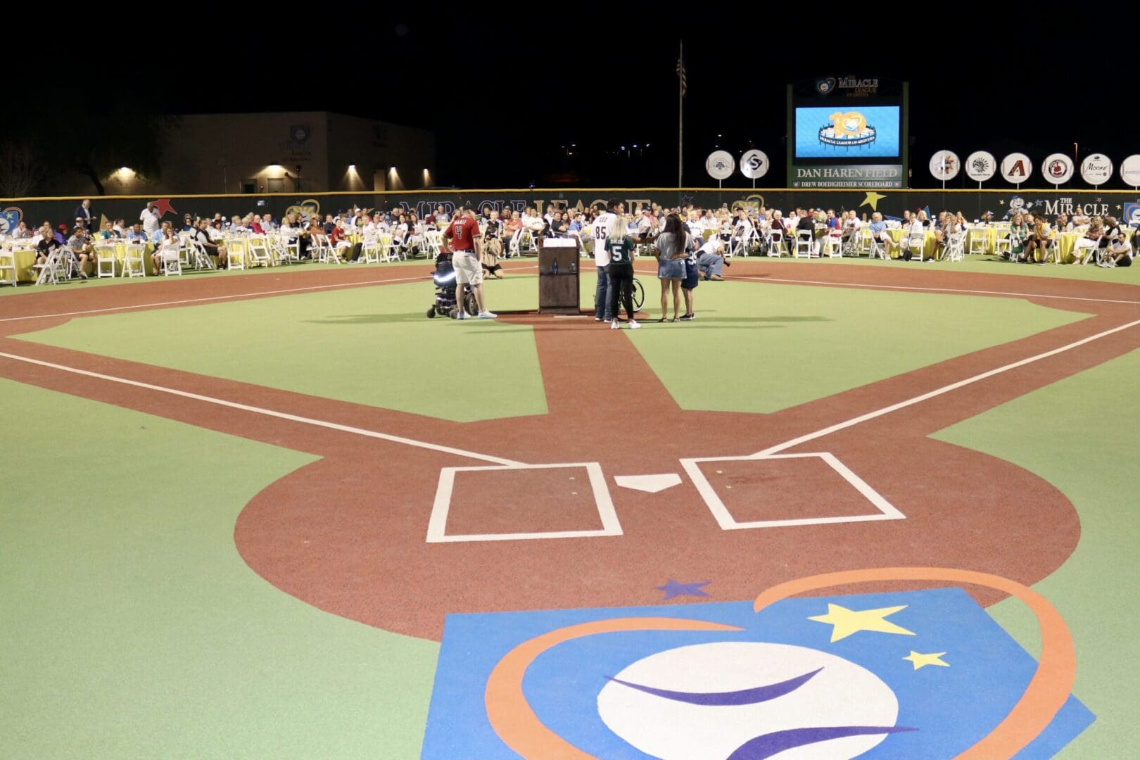 A group of people standing on a baseball field.