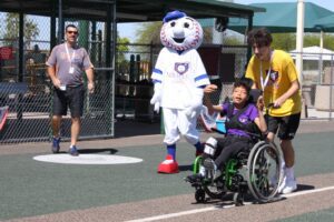 A baseball mascot helps a boy in a wheelchair.