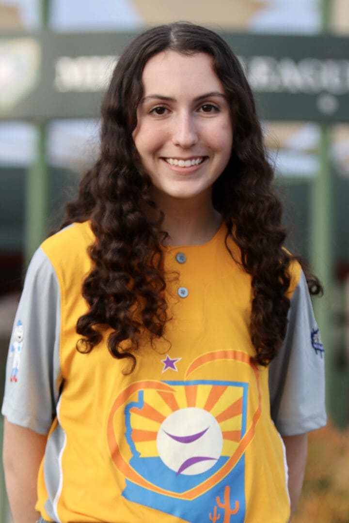 Smiling woman wearing a yellow baseball jersey.