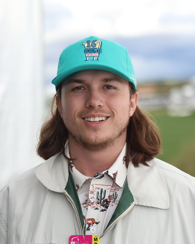 Man wearing a teal hat and a white shirt.