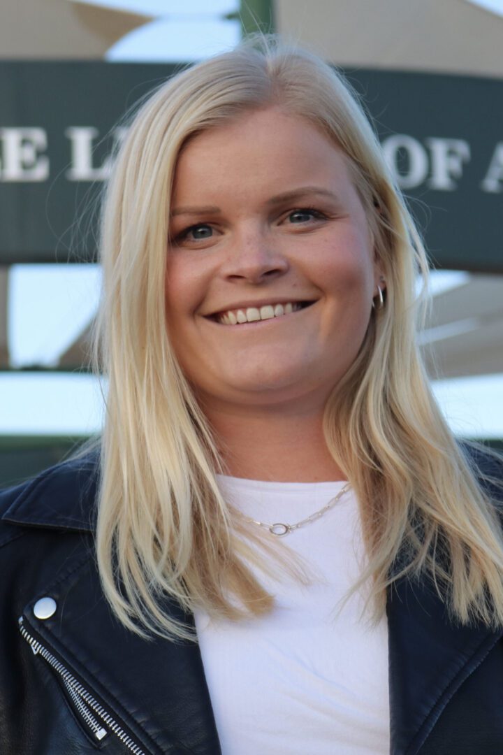 Smiling woman with blonde hair in a leather jacket.